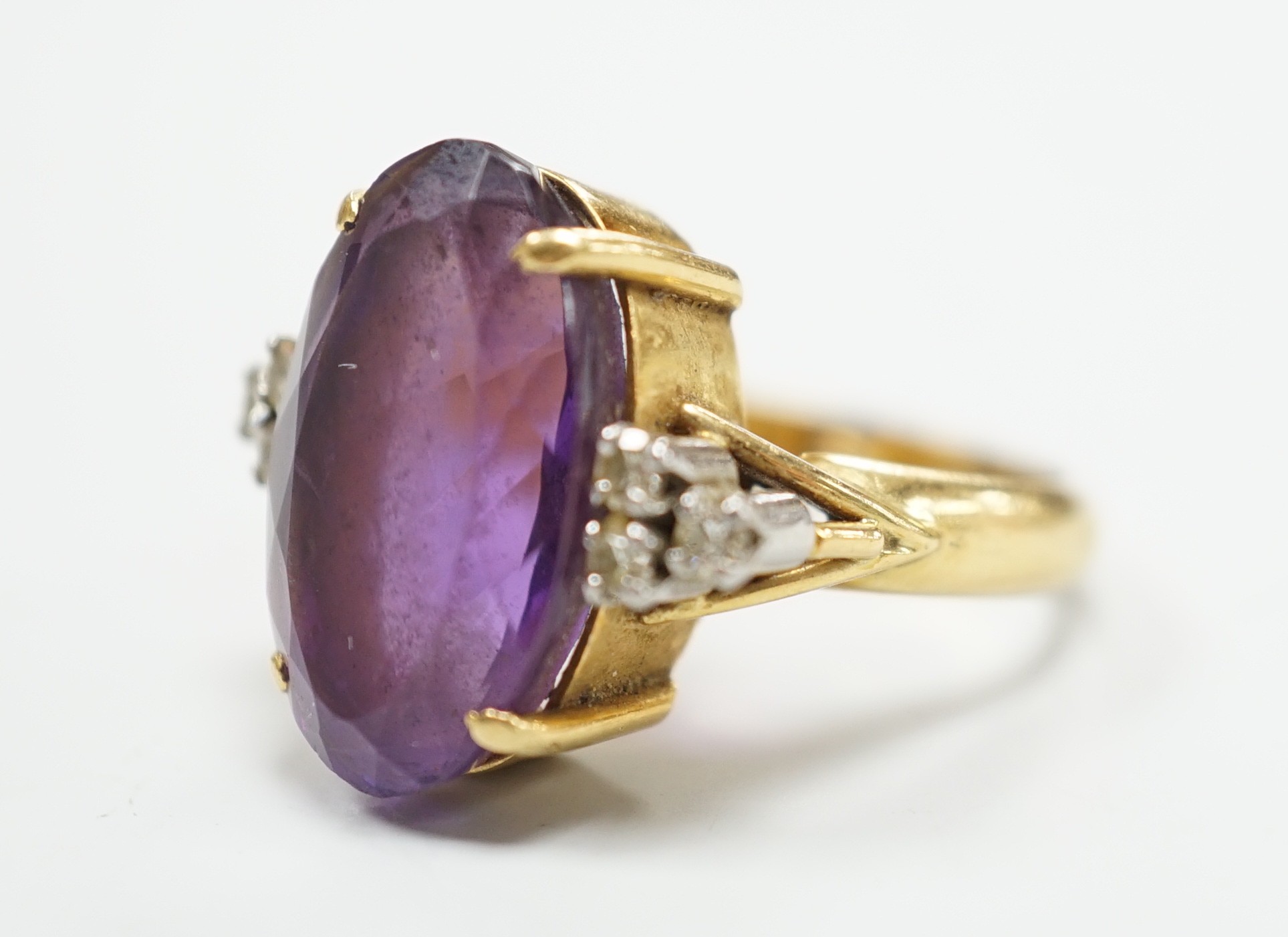 A yellow metal and oval cut amethyst set dress ring, with six stone diamond set shoulders, size O, gross weight 9.6 grams.